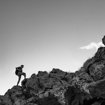 Mann, der einen Feldpass hinaufsteigt um sein Ziel zu erreichen